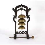 A Chinese table bell, the four graduated brass bells on a carved wood stand,