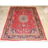 A modern decorative rug with central sky blue medallion to a scarlet ground,