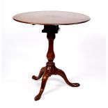 A George III mahogany table, the circular top on a birdcage action turned column and tripod base,