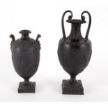 Two Wedgwood black basalt two-handled urns, the sides moulded with muses, impressed mark,