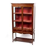 An Edwardian mahogany display cabinet banded in satinwood with platform beneath,