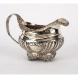 A silver cream jug, WH, London 1820, of half-ribbed form on paw feet, 11cm high,
