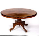 A Victorian walnut oval table with ebonised border on a turned column and carved quadruple support,