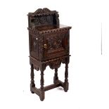A small carved oak cupboard on spiral legs,