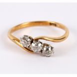 A three-stone diamond ring, of crossover design to an 18ct yellow gold shank,