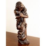 A carved oak wooden figure of a boy by a cooking pot,