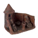 An Eberly red clay pottery group, figures seated outside a hut,