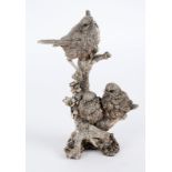 A filled silver model of three birds on a stump,
