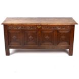 An oak chest with carved panel front and hinged cover,