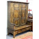 An elm bacon settle, the upper section enclosed by a pair of panel doors,