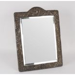 An embossed silver framed mirror, Birmingham 1902, with easel back, the bevelled glass 41.