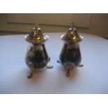 A pair of silver salt and pepper, each raised on three claw feet, 3.2oz.