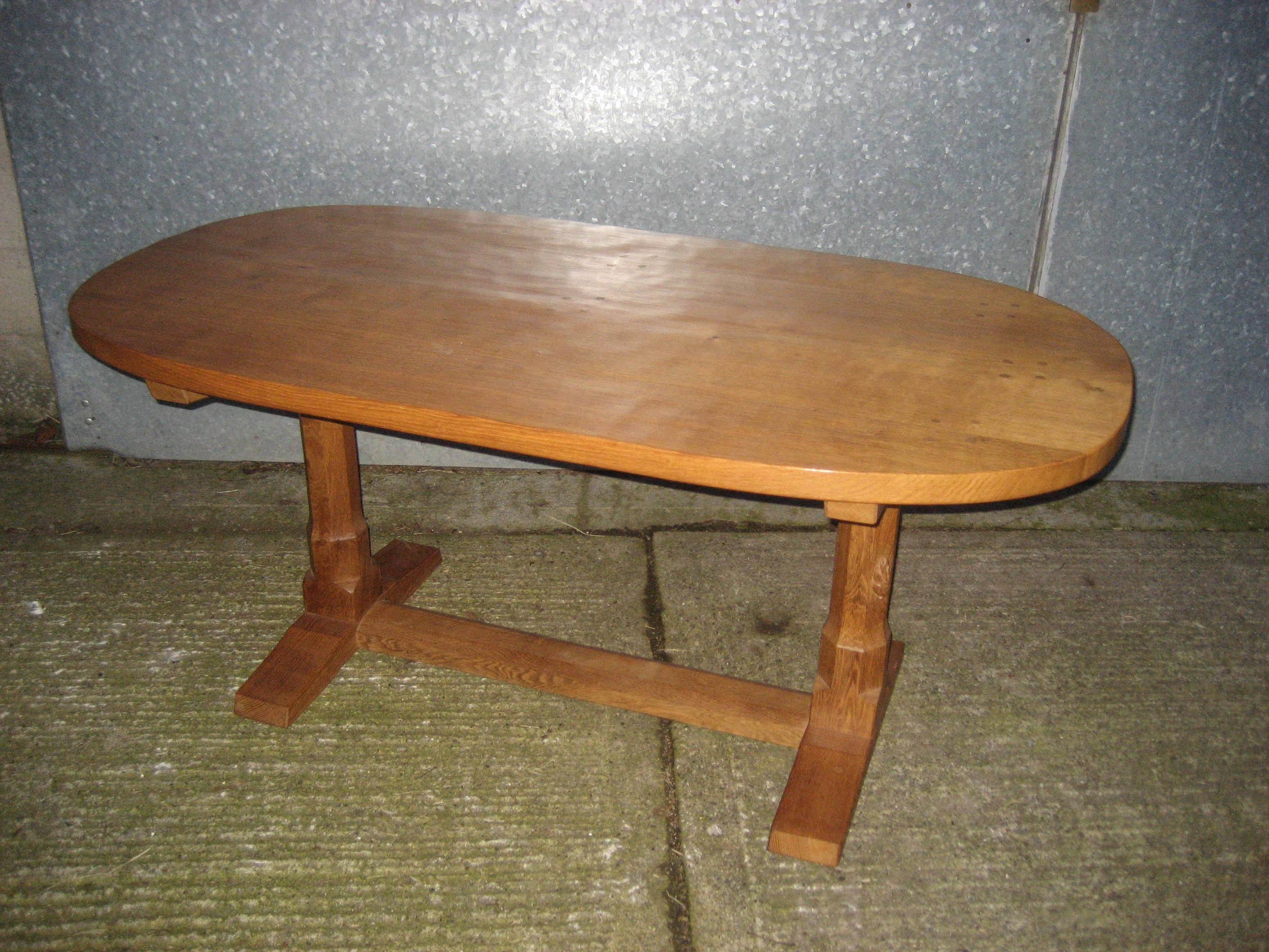 A Peter Heap oak dining table of oval from with large signature rabbit to one leg. Adzed top.