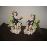 A pair of late 19th century/ early 20th century pottery cherub candle stick holders