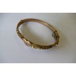 A 9ct gold bangle with embossed floral decoration (8.4g).