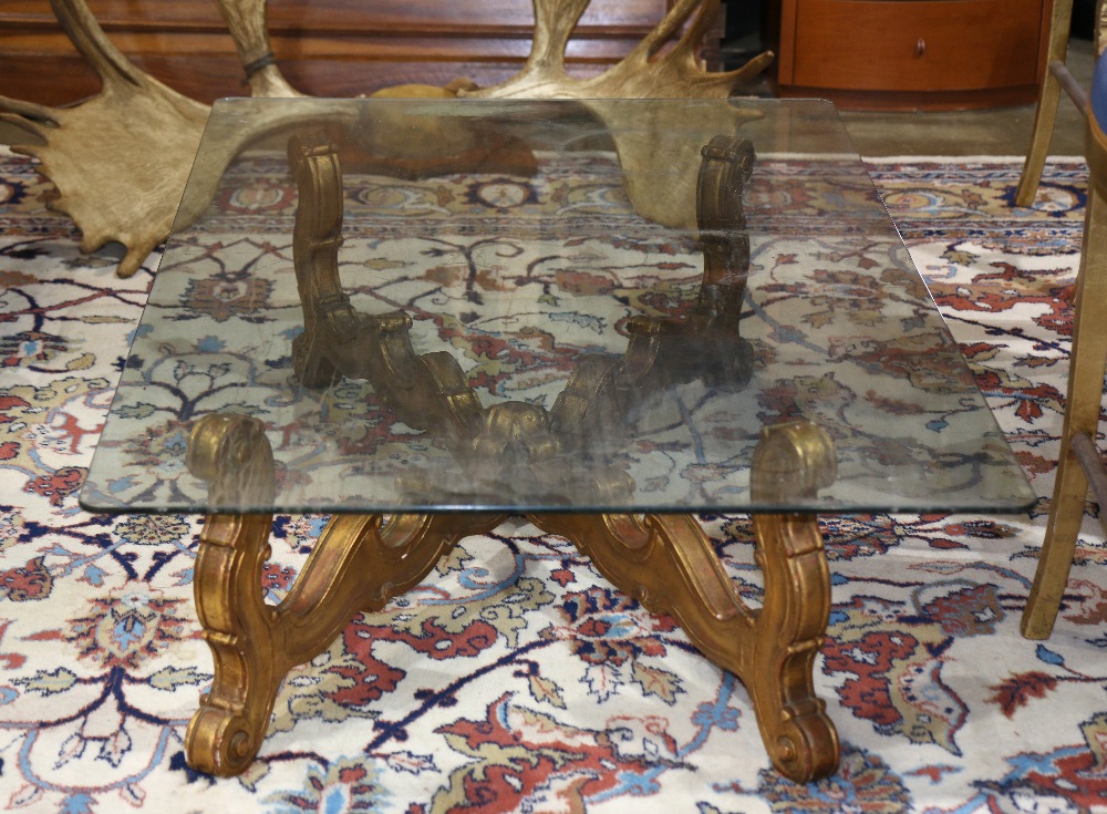 Hollywood Regency style cocktail table, having a glass rectangular top over the gilt composite "x"