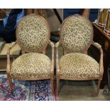 Pair of Louis XVI style fauteuils, having a carved foliate crest over upholstered back and seat,