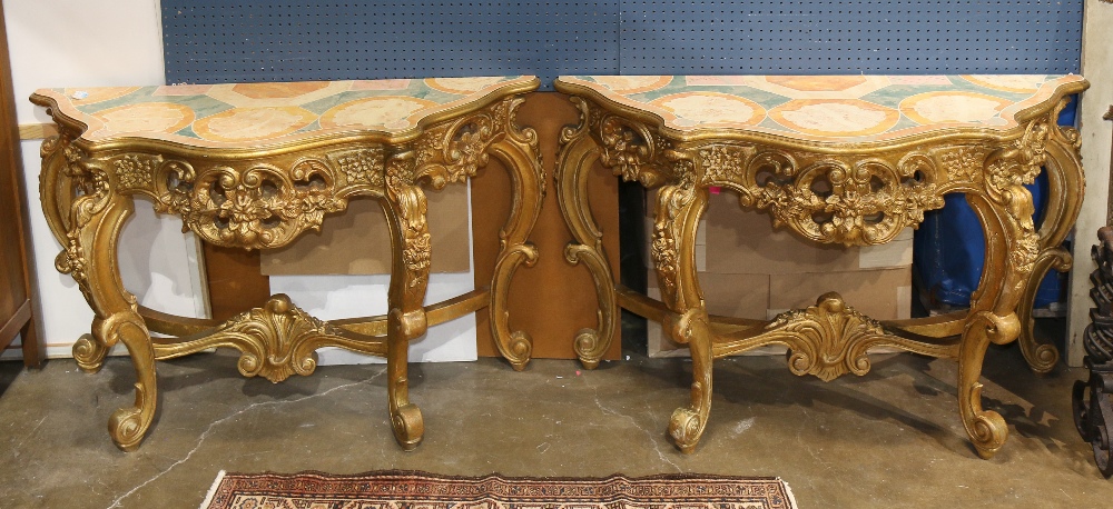 (lot of 2) Louis XV style console tables, each having a faux marble shaped top, above a giltwood