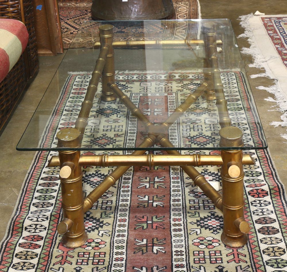 Hollywood Regency style low table, having a rectangular glass top, above the faux bamboo gilt