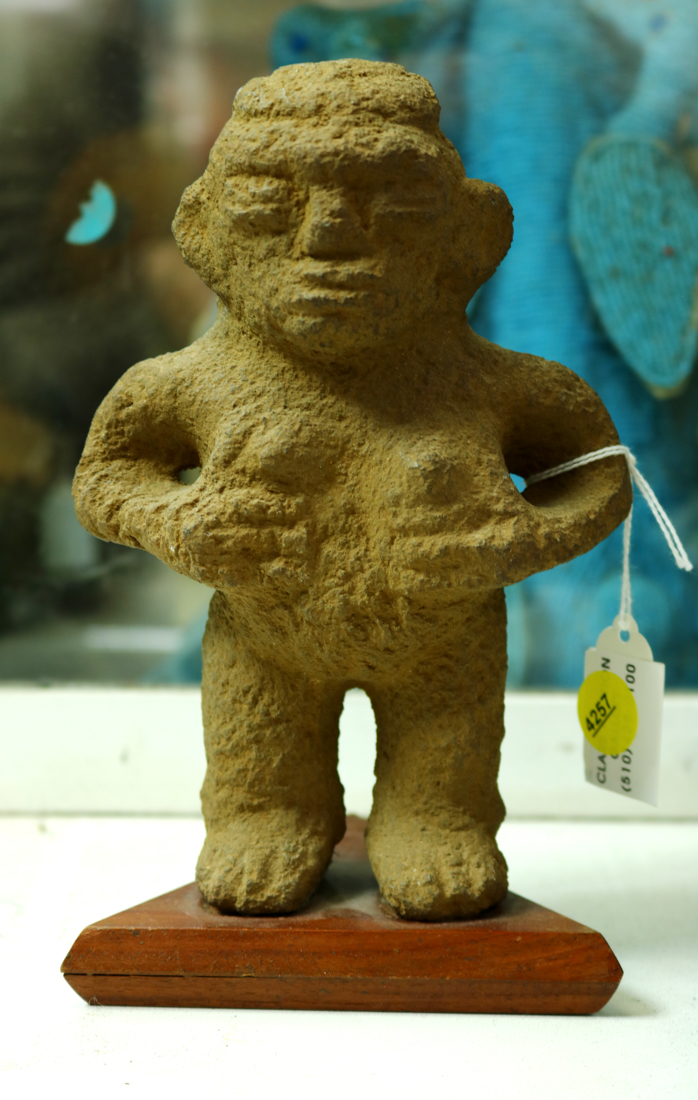 Pre-Columbian standing female stone figure, hands below her breasts, long striated hair down her