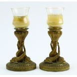 Pair of French gilt bronze figural candlesticks, each having a glass insert, above the dolphin