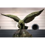 Patinated bronze figural eagle sculpture, depicted perched on a rocky shore, retains original