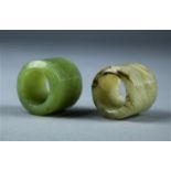 (lot of 2) Chinese hardstone thumb rings, one of celadon hue incised with bamboo; the other of off-