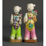 Pair of Chinese porcelain figures, each in the form of a child holding a sheng flute and a lotus
