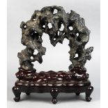 Chinese scholar's rock, the black matrix of arching form having multiple apertures, with wood stand,