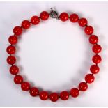 Coral bead and silver necklace Composed of (25) round coral beads, measuring approximately 18 mm,