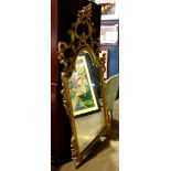 George III style gilt wood looking glass, having an ornately carved top over the shaped frame