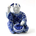 Japanese Kutani blue-and-white okimono, of a smiling karako beating a drum, base marked "Kutani [