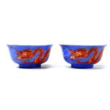 Pair of Chinese porcelain cups, each with a red dragon writhing on a blue ground with scrafito cloud