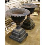 Pair of Victorian patinated metal garden urns, each having a scalloped border and rising on a square