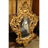 Rococo style giltwood carved looking glass, of shield form with floral sand shell carved reserves,