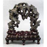 Chinese scholar's rock, the black matrix of arching form having multiple apertures, with wood stand,