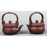 Pair of Chinese zisha teapots, with applique scrolls above the low slung body, with a bracket handle