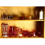 Two shelves of mostly cranberry glass, including a Mary Gregory tumbler, together with a lustre,