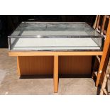 Glass display table, having a rectangular top with glass panels, above an oak base, 40"h x 60w x