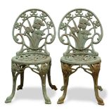 Pair of patinated cast iron garden chairs, each having an iris decorated back, and rising on