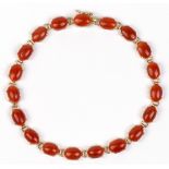 Coral and 14k yellow gold bracelet Composed of (19) oval coral cabochons, measuring approximately