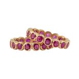 (Lot of 2) Ruby and 18k yellow gold eternity bands Each featuring (16) round-cut rubies, weighing