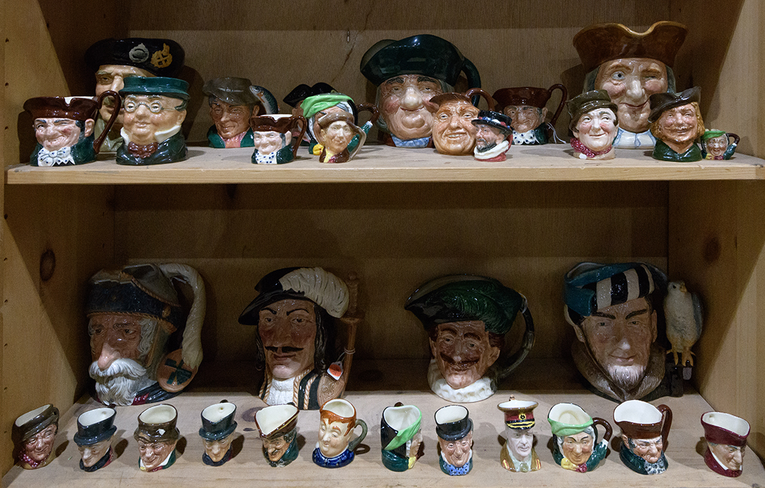 Two shelves of Royal Doulton character jugs, in various sizes including "Toby Philpotts," "Vicar