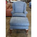 Queen Anne style wing back arm chair with ottoman, having blue upholstery and rising on pad feet,