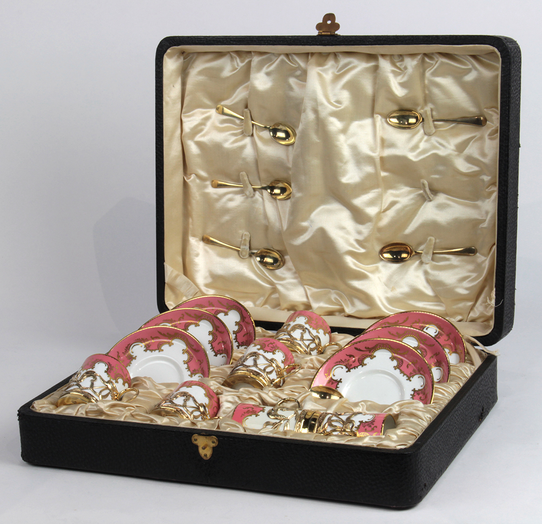 Cased Royal Crown Derby demitasse set for six, having a pink border with gilt accents on a white