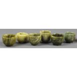 (lot of 16) Chinese hardstone small cups, of various shapes, each of bottled sea-green hue, raised