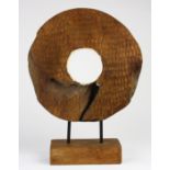 Carved wood sculpture on stand, in the form of a primitive wheel, the front with incised geometric