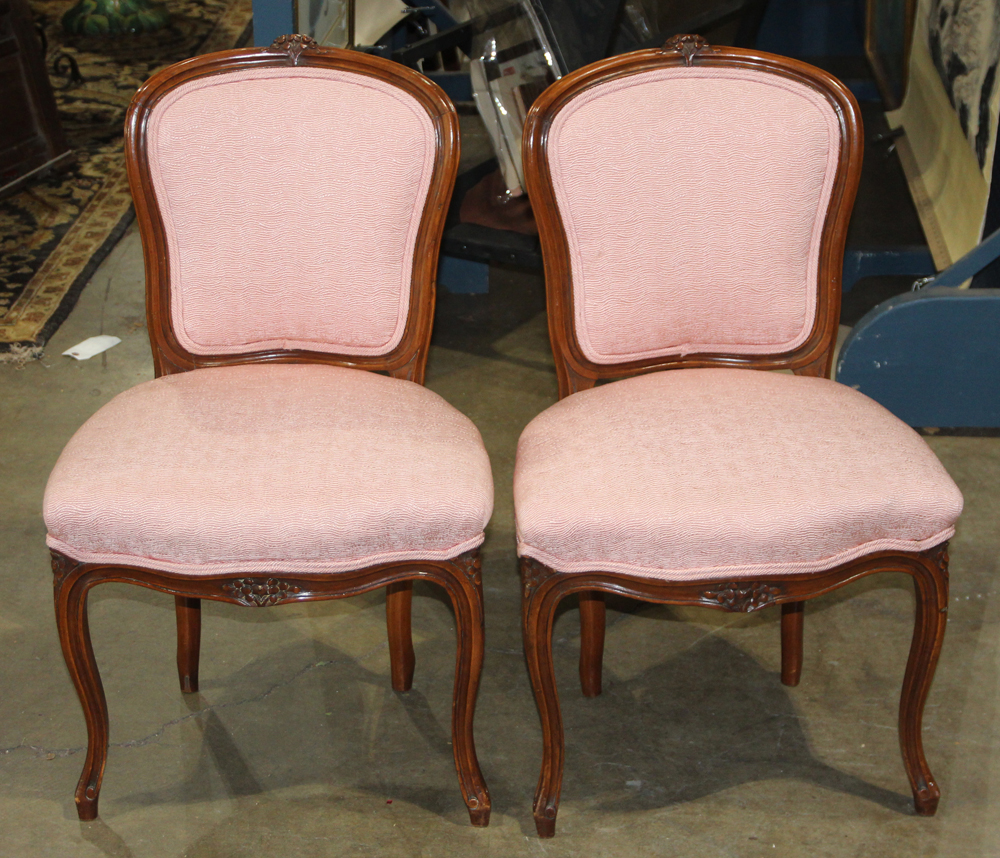 Pair of French walnut fauteuils, each having a shaped back with floral carved crest and rising on