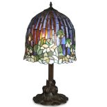 Tiffany style leaded glass floral table lamp, having a mushroom form shade above the patinated metal