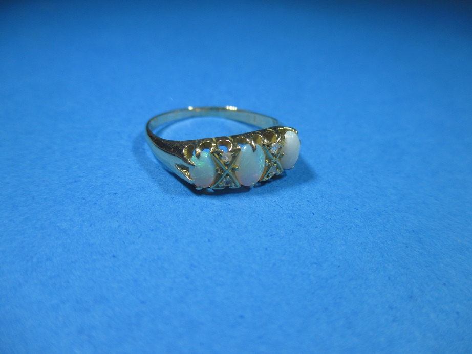 An 18ct gold ring set with diamonds and 3 opals, approx. size N